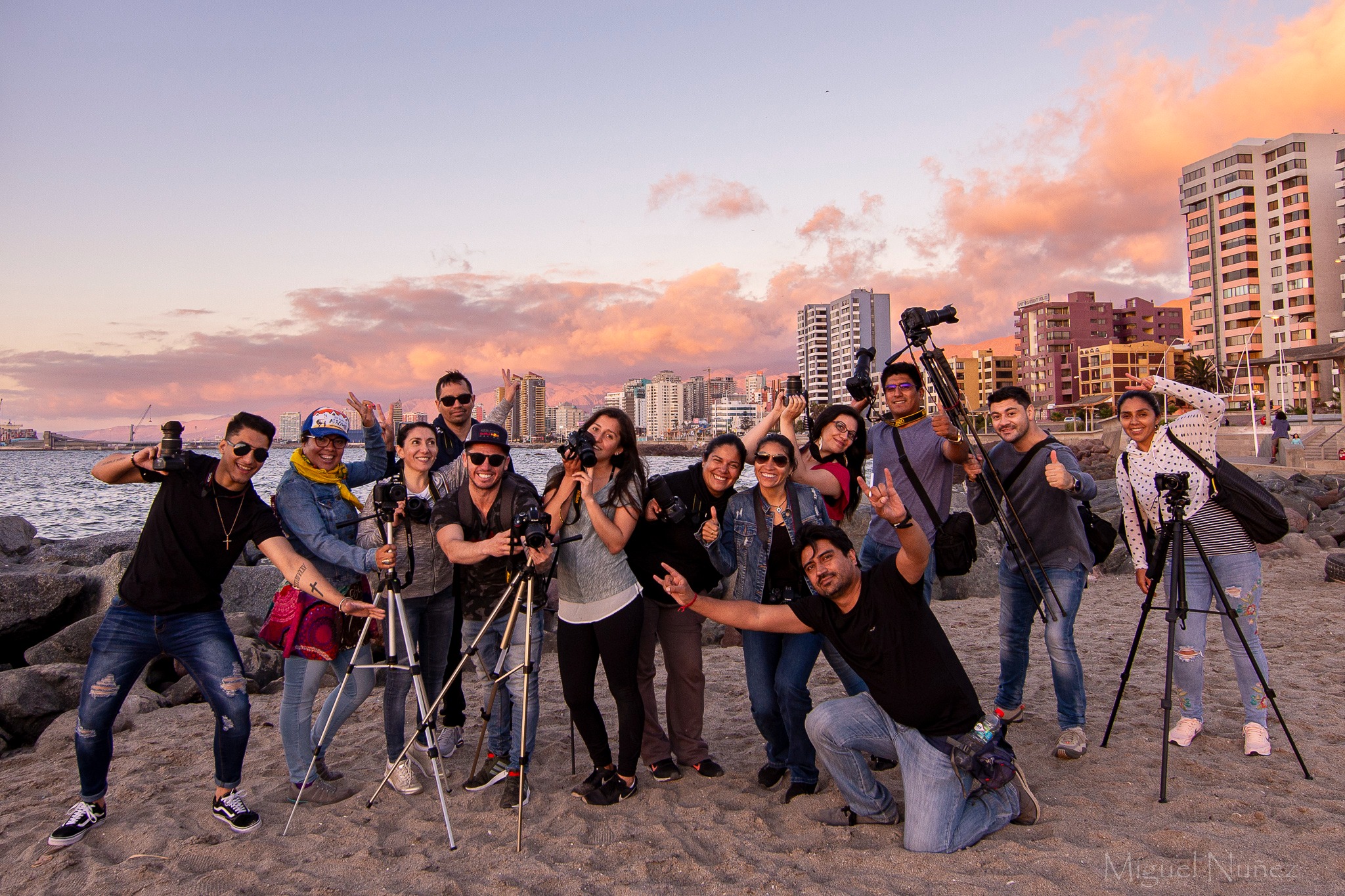 Grupo de participantes con cámaras al atardecer junto al mar